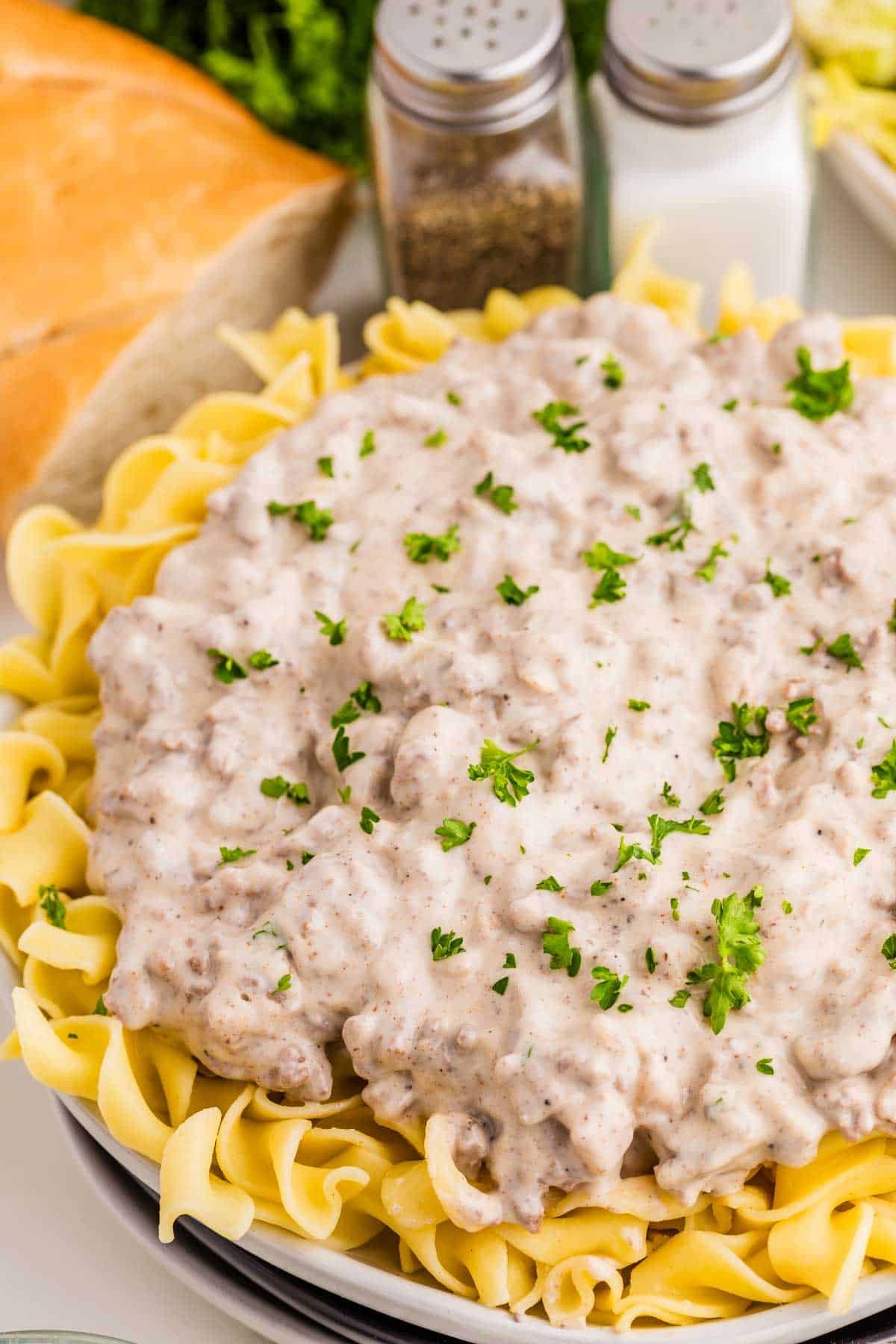 Ground beef stroganoff spooned over wide egg noodles and topped with chopped parsley. The creamy beef and mushroom sauce covers most of the noodles.