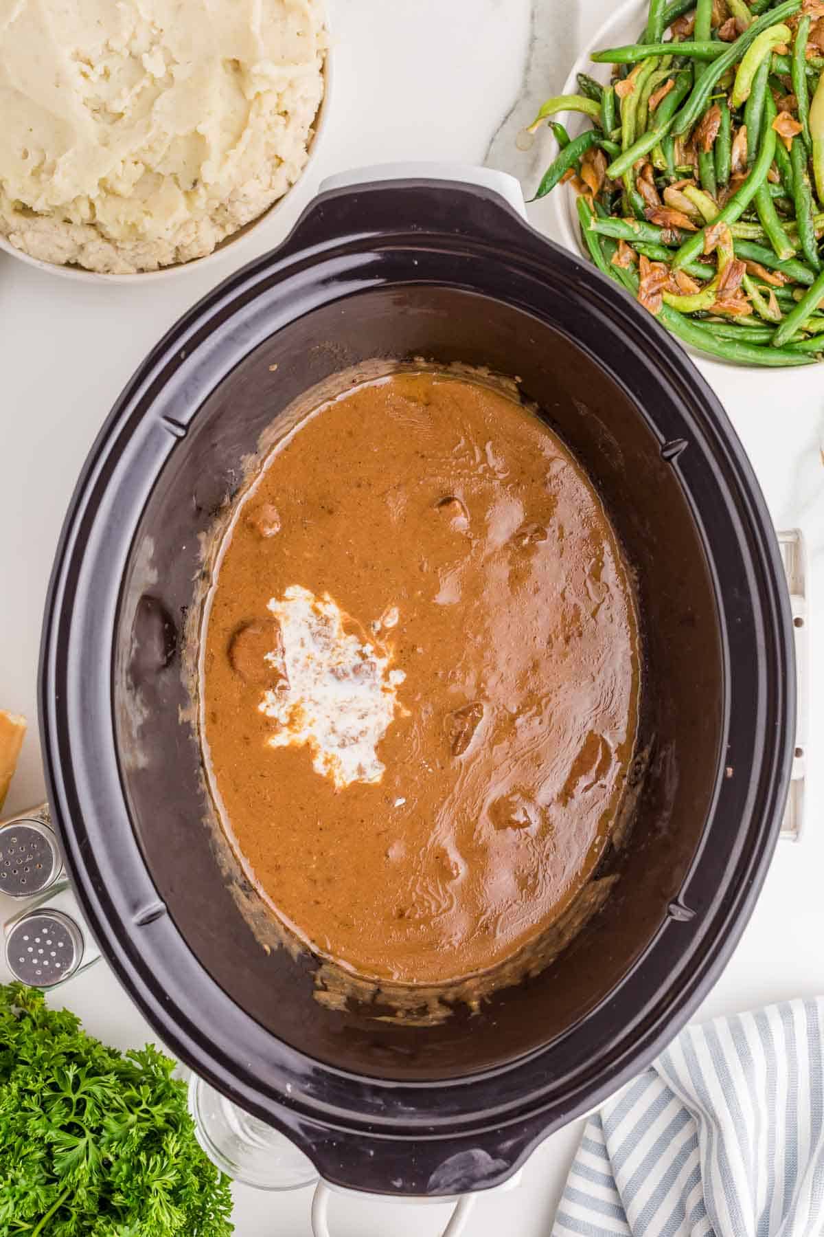 Cooked beef tips in thick brown gravy after several hours in the slow cooker. A cornstarch mixture has been added to help thicken the gravy before serving.
